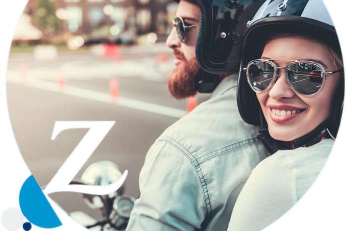 pareja con cascos y gafas de sol circulando en una moto