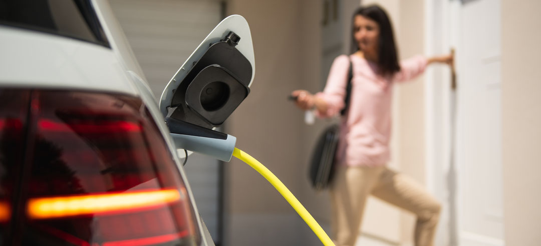 Mujer cerrando un coche eléctrico mientras carga