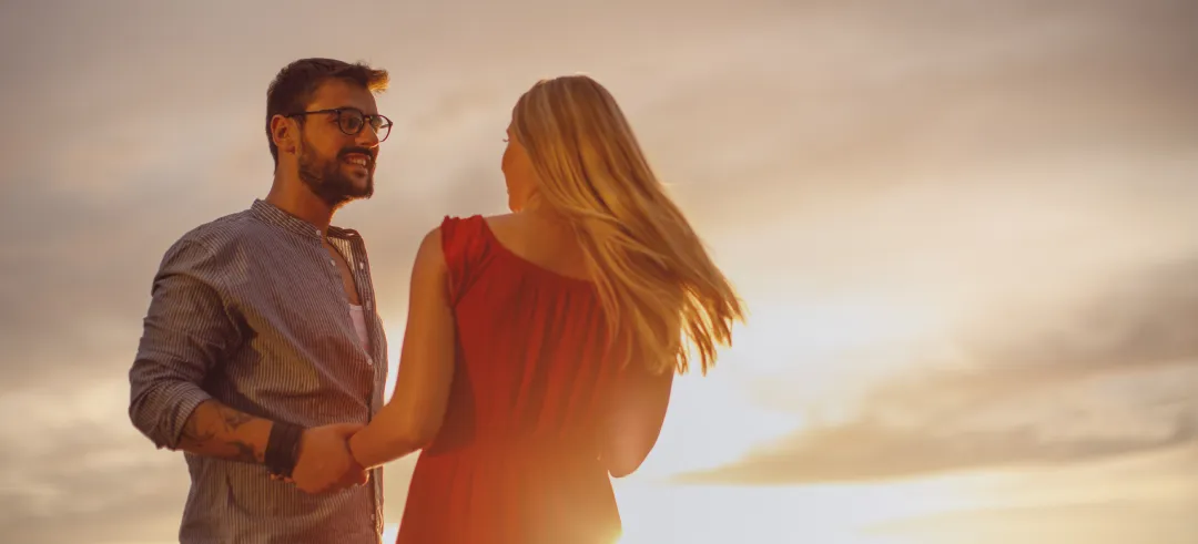 Pareja dándose las manos con el atardecer de fondo